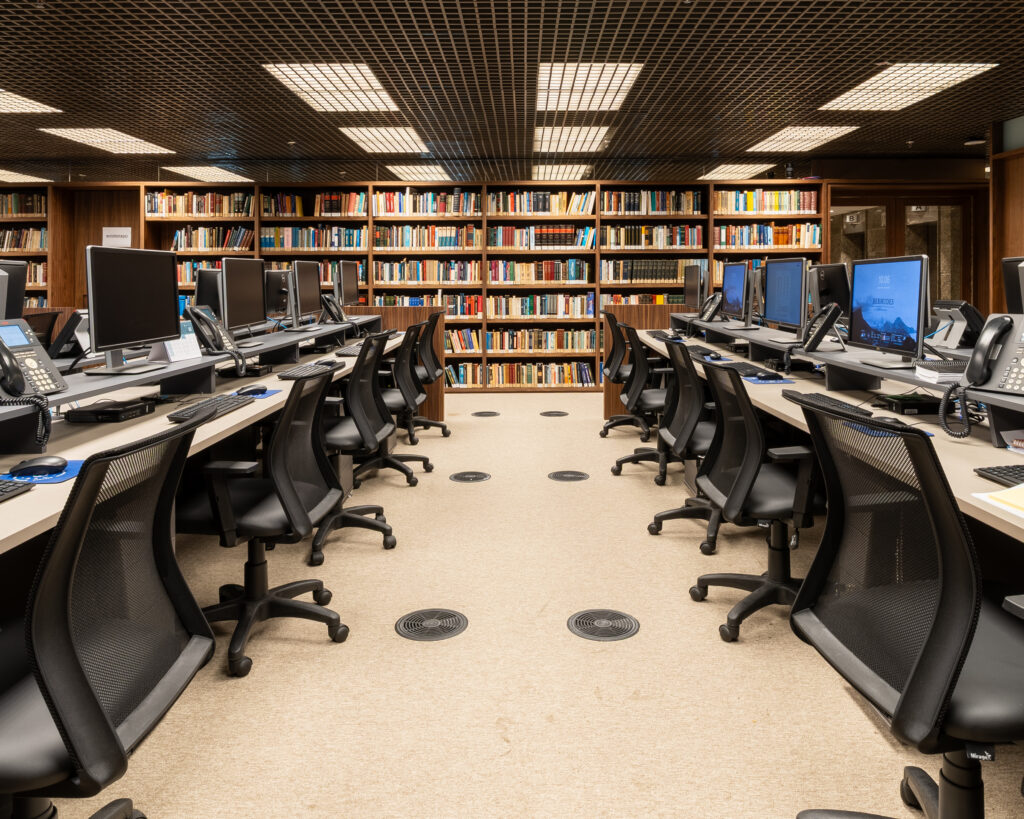 estações de trabalho em escritório de advocacia com cadeiras ergonômicas e layout organizado em ambiente com estante de livros
