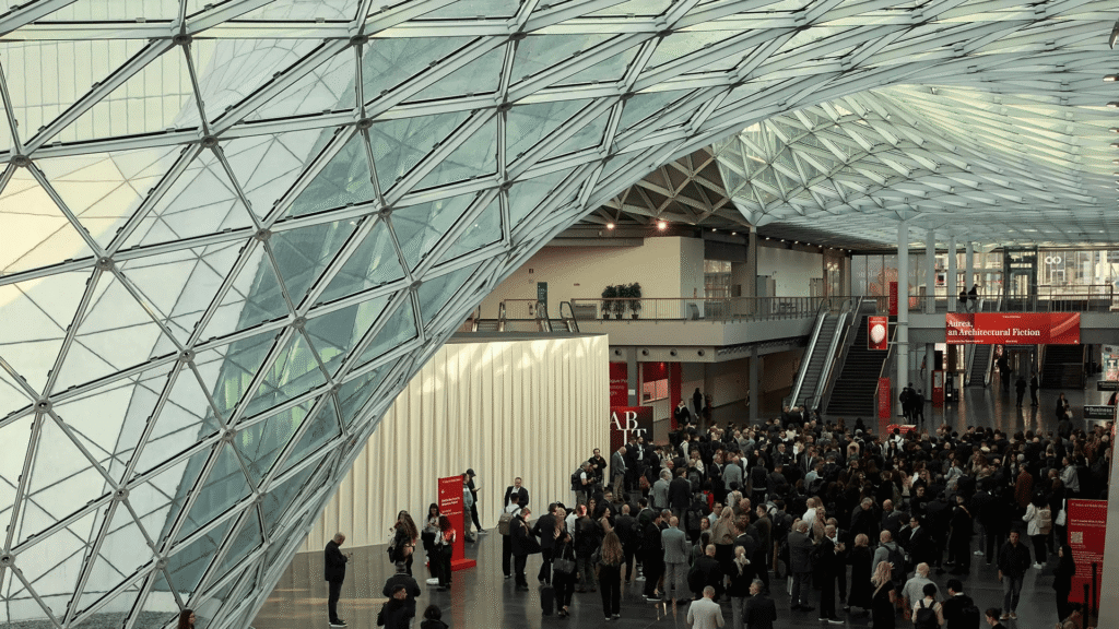 Salone del Mobile 2026: multidão sob teto de vidro geométrico em um dos maiores eventos globais de design e mobiliário contemporâneo.