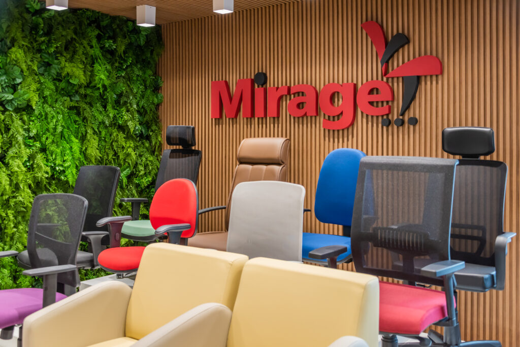 Showroom de mobiliário corporativo da Mirage Móveis com cadeiras de escritório, poltronas e painel ripado ao fundo.